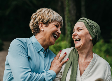 Two ladies laughing, one wearing a head scarf